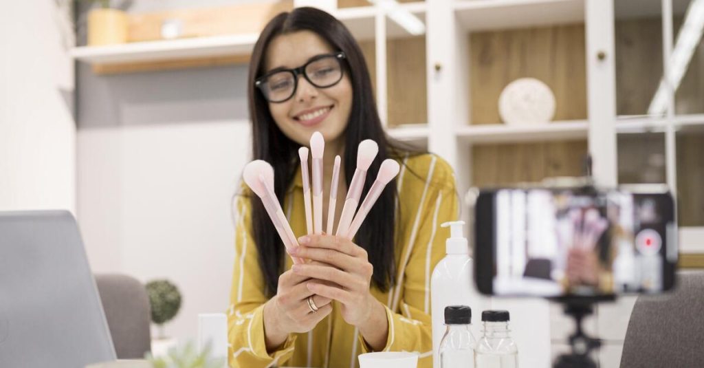 female vlogger home with laptop brushes 1